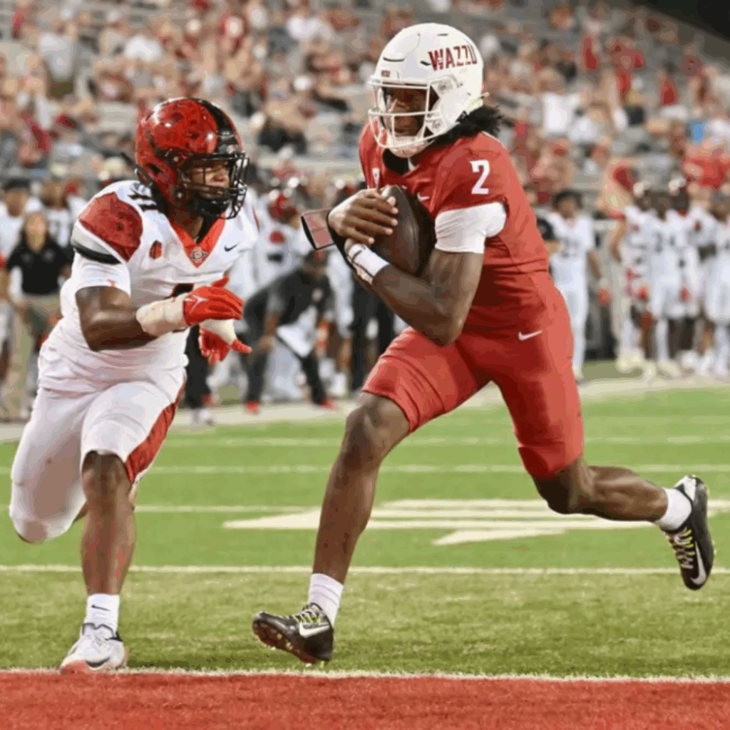 A WSU football player running into an endzone with a football.